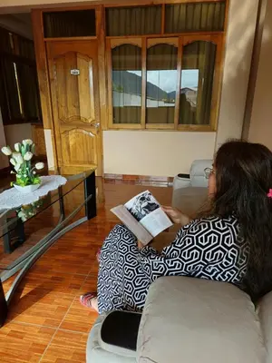 a woman sitting on a couch reading a book at Echevarria Oxapampa in Oxapampa