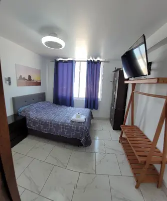a bedroom with a bed and a flat screen tv at Bravos Hospedaje Punta Negra in Punta Negra