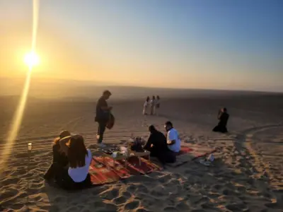 a group of people sitting on a blanket on the beach at Hospedaje Mayo Huacachina in Ica