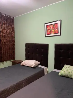 a hotel room with two beds and a window at Hospedaje Mayo Huacachina in Ica