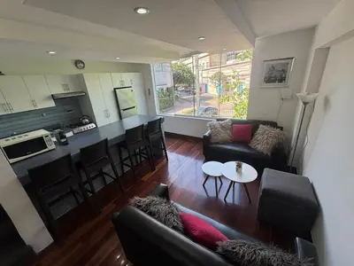 a living room with a couch and a table and a kitchen at Centrally located and comfortable duplex in Miraflores - Libertad1BR in Lima