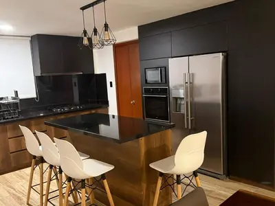 a kitchen with black cabinets and white bar stools at Welcoming apartment in Lima