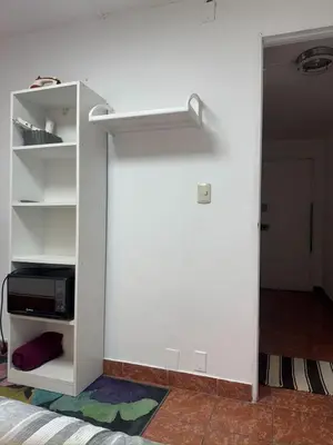 a room with a white wall with a book shelf at Miraflores, baño privado, ingreso independiente in Lima