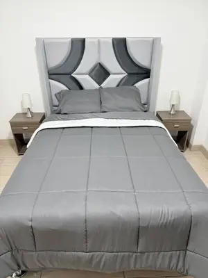 a bed with a gray bedspread and two night stands at Apartamento moderno a 5 minutos de Plaza Norte in Lima