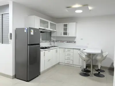 a kitchen with a stainless steel refrigerator and a table at Apartamento moderno a 5 minutos de Plaza Norte in Lima
