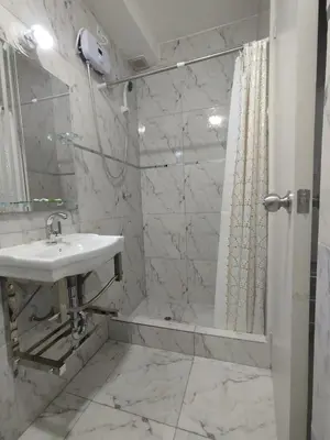 a white bathroom with a sink and a shower at Hostal San Ignacio Monterrico in Lima