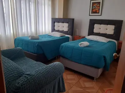 a room with two beds and a chair and a couch at Departamento turístico Rosaelena b&b 9 personas in Cusco
