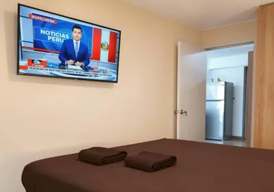 a bedroom with a television hanging on the wall at E 24h Urban Comfort 1BR 302 in Lima