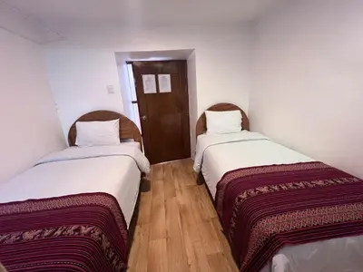 two beds in a small room with wooden floors at Pakari wasi inn in Cusco