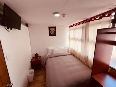 a small room with a bed and a tv at Pakari wasi inn in Cusco