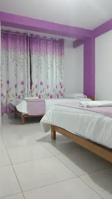 a bedroom with two beds and purple curtains at Hospedaje Bella Acuarela in Oxapampa