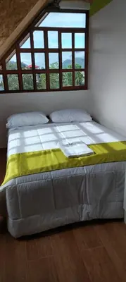 a large bed in a room with two windows at Hospedaje Bella Acuarela in Oxapampa