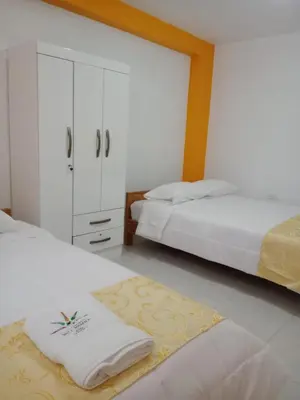 a bedroom with two beds and a dresser with towels at Hospedaje Bella Acuarela in Oxapampa