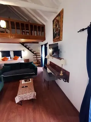 a bedroom with a bed and a desk and a piano at Apartamento Familiar con balcón y vista a la Ciudad, Centro in Cusco