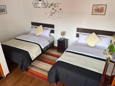a bedroom with two beds and a rug at Cusco and Rock in Cusco