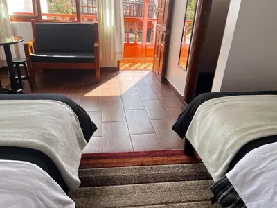 a room with two beds and a chair and a window at Cusco and Rock in Cusco
