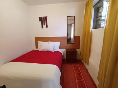 a bedroom with a bed with a red blanket at Yuraq Wasicha in Cusco