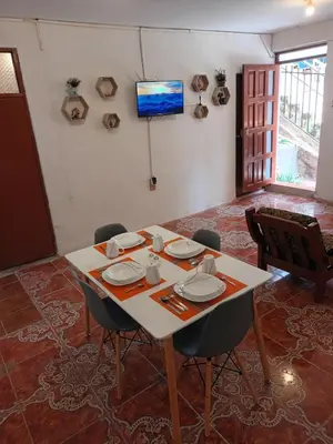 a table with chairs and a television in a room at Yuraq Wasicha in Cusco