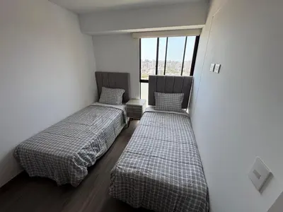two beds in a room with a window at Cozy bedroom in Miraflores with rooftop pool in Lima