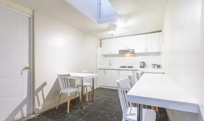 a kitchen with white cabinets and white tables and chairs at Corazón de Cusco 2 in Cusco