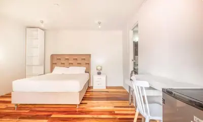 a white bedroom with a bed and a desk at Corazón de Cusco 2 in Cusco