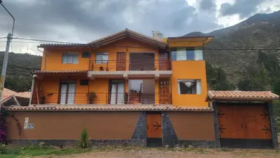 a yellow house with orange doors and a mountain at Chakana Wasi in Calca