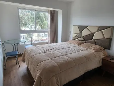 a bedroom with a bed and a table and a window at Departamento equipado, cómodo, tranquilo y céntrico in Lima