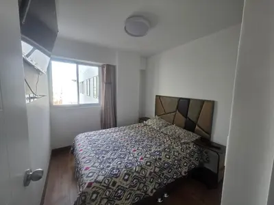 a bedroom with a bed with a comforter and a window at Departamento equipado, cómodo, tranquilo y céntrico in Lima