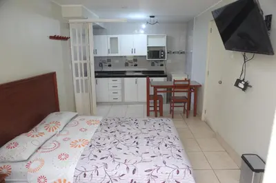 a bedroom with a bed and a kitchen with a table at Hostal Real in Lima