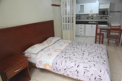 a small bedroom with a bed and a kitchen at Hostal Real in Lima