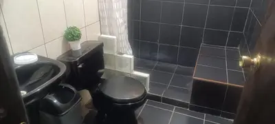a bathroom with a black toilet and a sink at Cozy Rural House in Apata - Jauja