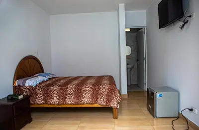 a bedroom with a bed and a television on the wall at Cieneguilla Casa in Cieneguilla
