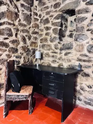 a black desk with a chair and a stone wall at Stone house in Ollantaytambo in Ollantaytambo