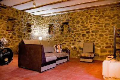 a room with a stone wall with a couch and a guitar at Stone house in Ollantaytambo in Ollantaytambo