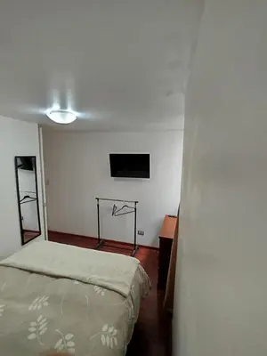 a bedroom with a bed and a tv on the wall at Cómoda y céntrica habitación Larcomar in Lima