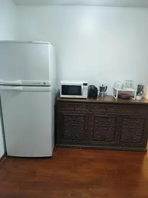 a kitchen with a white refrigerator and a microwave at Amplia y céntrica habitación con vistas Larcomar in Lima