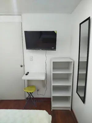 a bedroom with a desk and a tv on the wall at Acogedora y céntrica habitación Larcomar in Lima