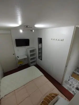 a small bedroom with a bed and a television at Acogedora y céntrica habitación Larcomar in Lima