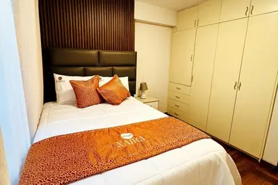 a bedroom with a large bed with orange pillows at Departamento en Cusco NAIRA in Cusco