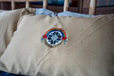 a pillow with a patch on it sitting on a bed at Pachamama Hampina Wasi Ancestral Center in Urubamba