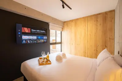 a bedroom with a white bed with a tv on the wall at MMXX Apartments by Vibrant in Lima
