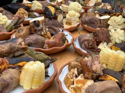 a table topped with plates of food with corn on the cob at Cabañas lago piuray in Chinchero