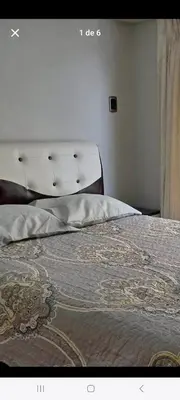 a bed in a bedroom with a white headboard at Hostal Qori in Urubamba