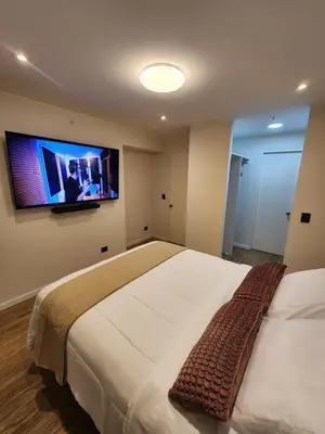 a bedroom with a large bed with a tv on the wall at Elegante Departamento de Estreno en Centro Financiero in Lima
