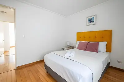 a bedroom with a large white bed with a wooden headboard at Central Bloom Miraflores in Lima