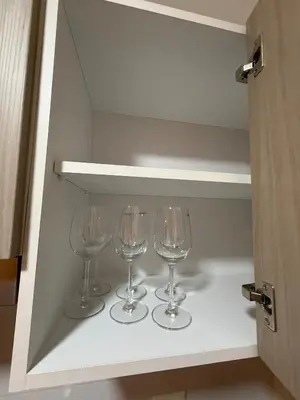 three wine glasses sitting on a shelf in a cabinet at Apartment in Victoria in Lima