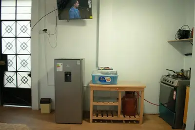 a kitchen with a refrigerator and a table and a television at Mini departamento con cochera in Ayacucho
