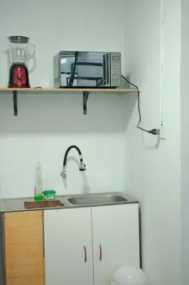 a kitchen with a sink and a microwave on a shelf at Mini departamento con cochera in Ayacucho
