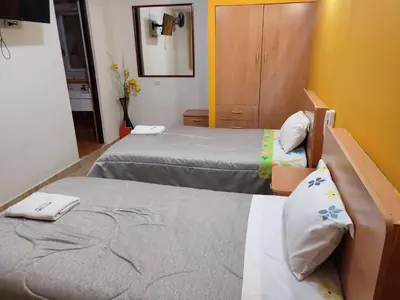 a hotel room with two beds and a mirror at Hotel Misky Samay in Ayacucho