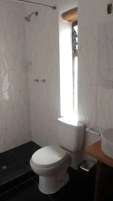 a white bathroom with a toilet and a window at Casa tarawasy hostel in Urubamba